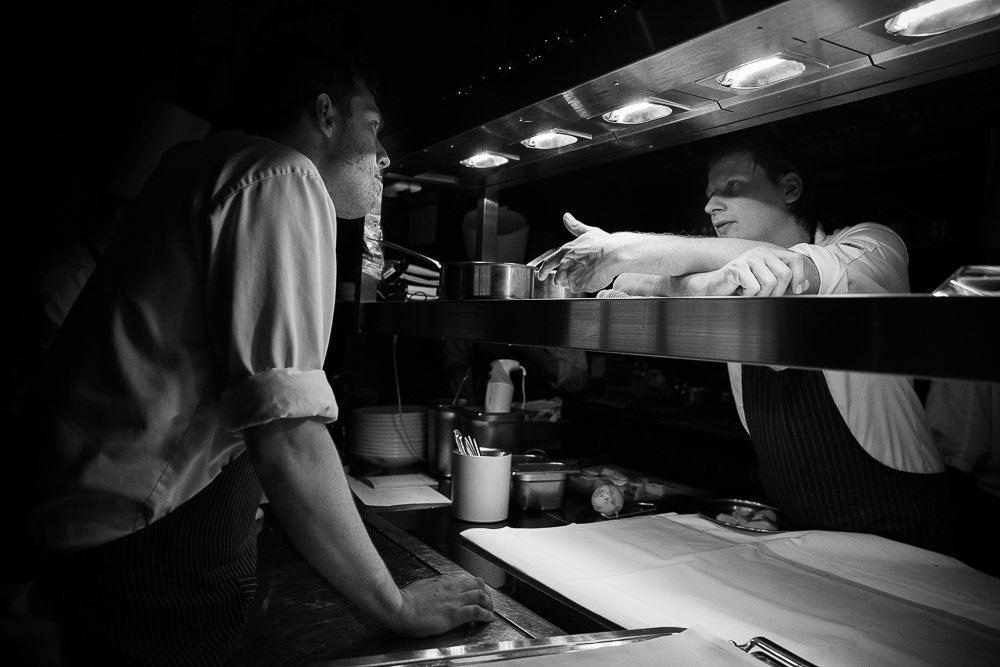 Twee koks in overleg aan de pass in de keuken